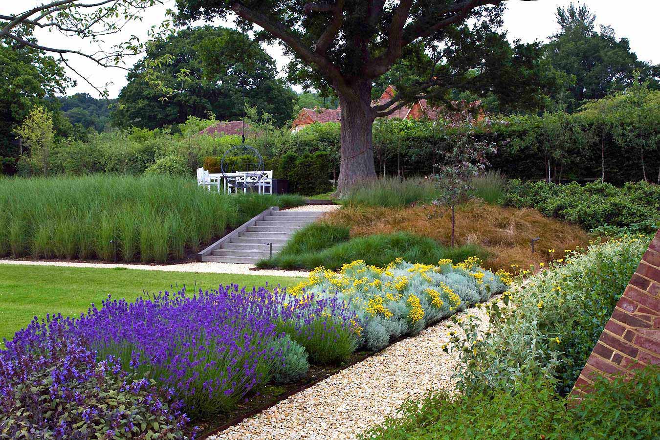Gravel pathway and stone steps with bold drifts of colourful planting and mature trees. Rae Wilkinson Garden and Landscape Design.