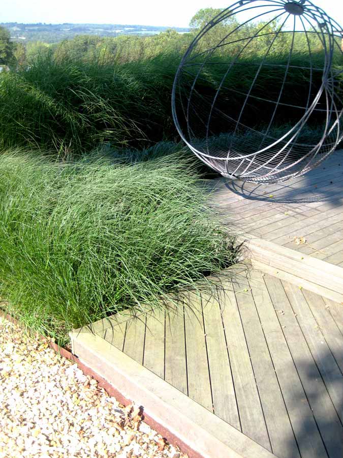 Detail of timber sundeck with foreground grasses. Rae Wilkinson Garden and Landscape Design - Garden Designer Sussex, Surrey, London, South-East England